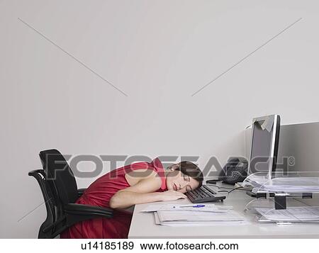 Stock Photo - Female office worker asleep at desk in office. Fotosearch