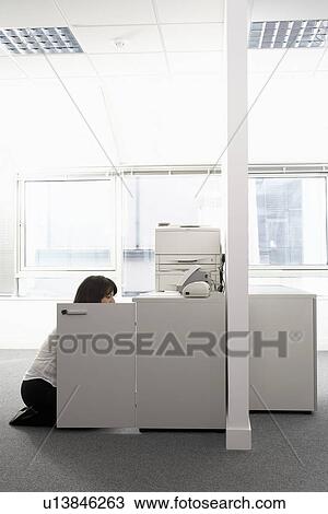 Female office worker kneeling in front of open cabinet in office side view View Large Photo Image Stock Image - Female office worker kneeling in front of open cabinet in office side view. Fotosearch
