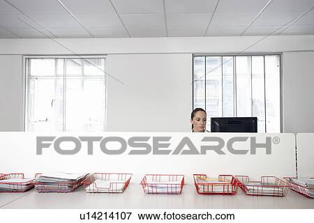 Female office worker using computer in office cubicle behind trays with documents View Large Photo Image Stock Photo - Female office worker using computer in office cubicle behind trays with documents. Fotosearch