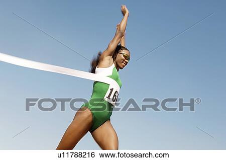 Stock Photograph - Female runner winning race side view. Fotosearch