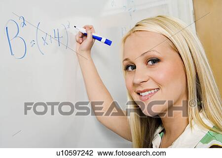 Stock Image - Female student writing equation on whiteboard (portrait). Fotosearch