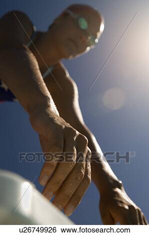 Stock Photograph - Female swimmer on starting blocks focus on hands (low angle view). Fotosearch