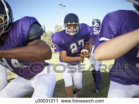 Football player running behind linemen on field View Large Photo Image Stock Image - Football player running behind linemen on field. Fotosearch