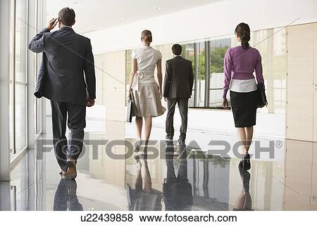 Stock Photo - Four Businesspeople Walking in Office Corridor. Fotosearch