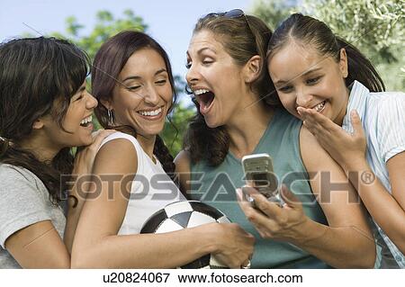 Stock Photo - Four women laughing at mobile phone display.. Fotosearch