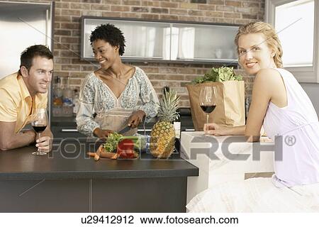 Stock Image - Friends preparing dinner together portrait. Fotosearch