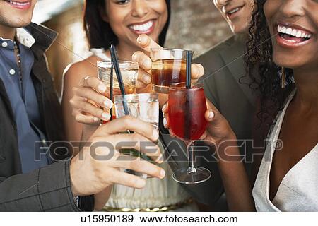 Stock Photo - Friends toasting in bar close up on glasses. Fotosearch