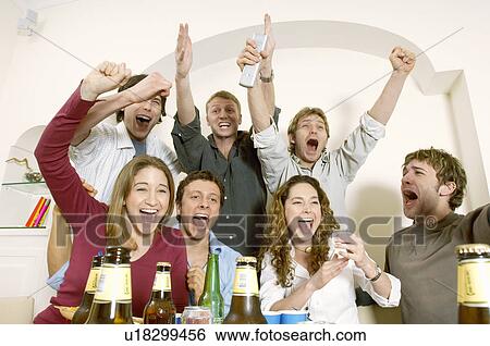 Stock Photograph - Friends watching TV and celebrating. Fotosearch