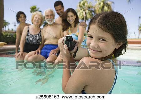 Girl (10-12) in swimming pool video taping brother (13-15) parents and grandparents portrait. View Large Photo Image Stock Image - Girl (10-12) in swimming pool video taping brother (13-15) parents and grandparents portrait.. Fotosearch