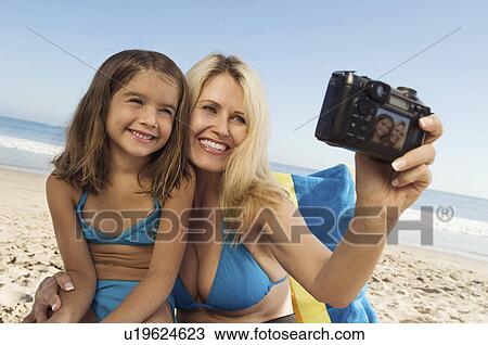Girl and mother photographing themselves on beach View Large Photo Image Stock Image - Girl and mother photographing themselves on beach. Fotosearch