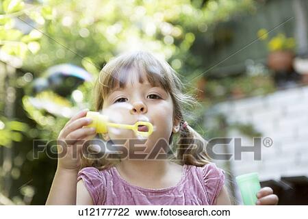 Girl Blowing Soap Bubbles in backyard close up View Large Photo Image Stock Image - Girl Blowing Soap Bubbles in backyard close up. Fotosearch