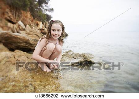 Girl squatting on rock at edge of water portrait View Large Photo Image Stock Image - Girl squatting on rock at edge of water portrait. Fotosearch