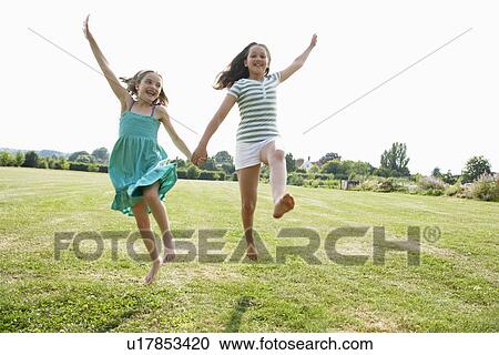 Girls Running and jumping Hand in Hand through field View Large Photo Image Stock Image - Girls Running and jumping Hand in Hand through field. Fotosearch