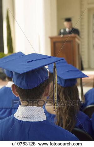 Stock Photo - Graduates listening to speaker outside back view. Fotosearch