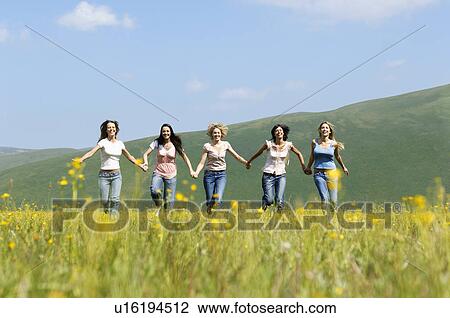 Group of friends running through mountain field front view View Large Photo Image Stock Image - Group of friends running through mountain field front view. Fotosearch