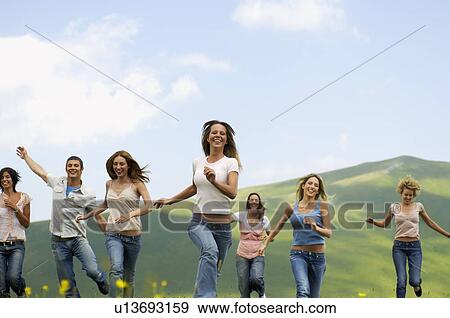 Group of friends running through mountain field front view View Large Photo Image Stock Photo - Group of friends running through mountain field front view. Fotosearch
