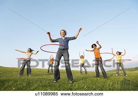Group of friends using hula hoops in mountain field low angle view View Large Photo Image Stock Photography - Group of friends using hula hoops in mountain field low angle view. Fotosearch