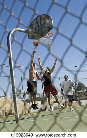 Stock Photo - Group of young men playing basketball. Fotosearch