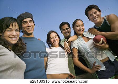 Stock Photography - Group of young people outdoors one young woman holding football low angle view.. Fotosearch
