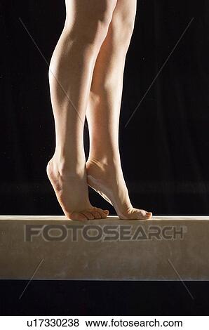 Stock Photo - Gymnast (13-15) on balance beam low section. Fotosearch