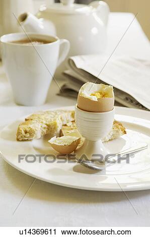 Stock Image - Half-Eaten Hard-Boiled Egg on dining room table With Tea. Fotosearch