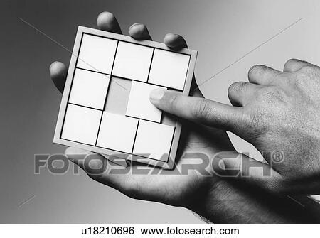 Stock Photograph - Hands holding slide puzzle (b&w) (close-up). Fotosearch