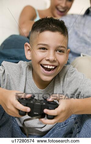 Happy Boy sitting on living room floor Playing Video Games close up View Large Photo Image Picture - Happy Boy sitting on living room floor Playing Video Games close up. Fotosearch
