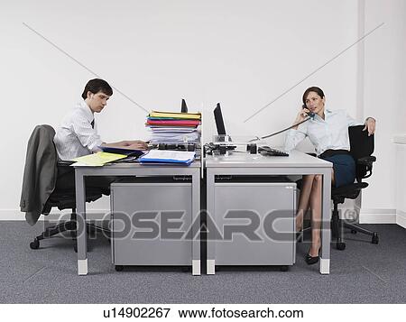 Hardworking man and relaxed woman in office View Large Photo Image Stock Photo - Hardworking man and relaxed woman in office. Fotosearch