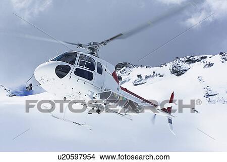 Helicopter flying over snowy mountain peaks View Large Photo Image Picture - Helicopter flying over snowy mountain peaks. Fotosearch