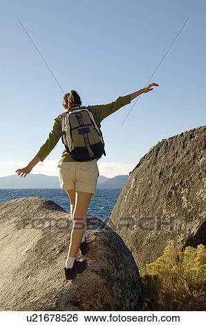 Stock Photograph - Hiker balancing on boulder at coast. Fotosearch