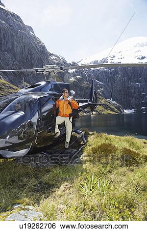 Hiker climbing out of helicopter on mountain top View Large Photo Image Stock Photograph - Hiker climbing out of helicopter on mountain top. Fotosearch