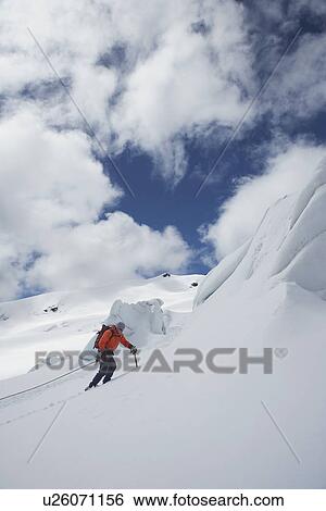 Stock Photograph - Hiker going up snowy mountain slope. Fotosearch