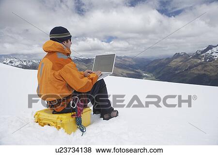 Hiker using laptop on snowy mountain peak back view View Large Photo Image Stock Photo - Hiker using laptop on snowy mountain peak back view. Fotosearch