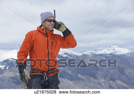 Stock Photo - Hiker using walkie-talkie on mountain peak. Fotosearch