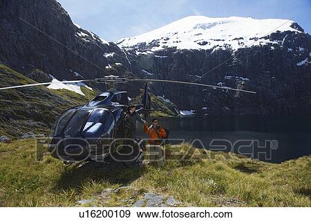 Hikers climbing out of helicopter on mountain peak View Large Photo Image Stock Photo - Hikers climbing out of helicopter on mountain peak. Fotosearch