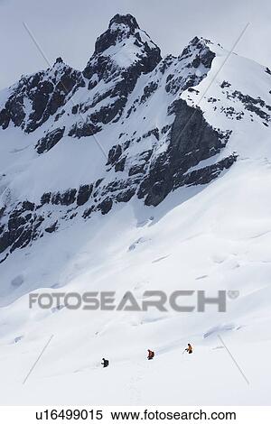 Stock Photography - Hikers headed for distant peak in snow back view. Fotosearch
