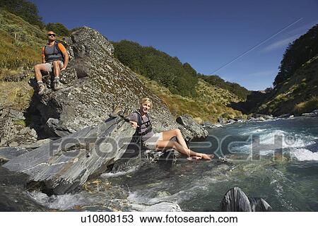 Stock Image - Hikers relaxing by river. Fotosearch