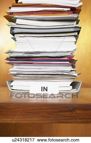 Stock Photo - Inbox with stack of paperwork on desk. Fotosearch