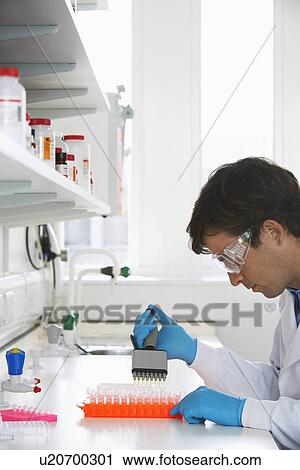Stock Image - Lab Worker Processing Vials. Fotosearch