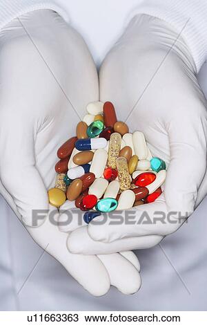 Stock Image - Lab Worker with Hands Full of coloured Pills. Fotosearch