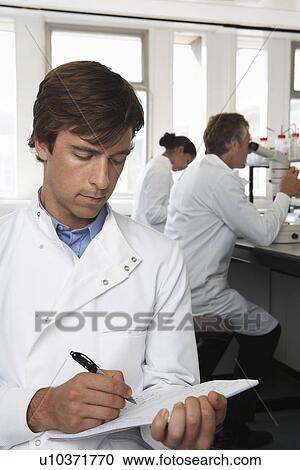 Lab Worker writing colleagues behind View Large Photo Image Stock Image - Lab Worker writing colleagues behind. Fotosearch
