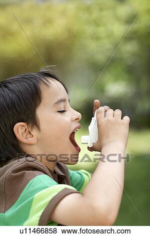 Stock Photo - Little boy in park using inhaler. Fotosearch