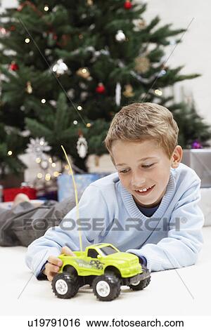 Stock Photograph - Little Boy Playing with Toy Truck by christmas tree. Fotosearch