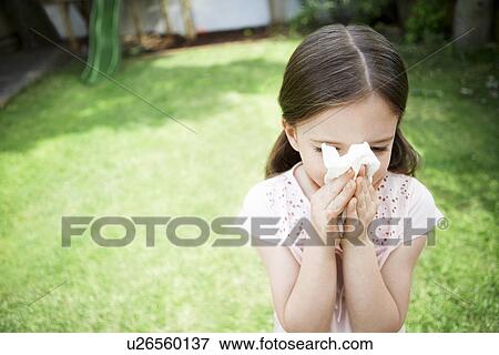 Stock Photo - Little girl in backyard blowing nose close up. Fotosearch