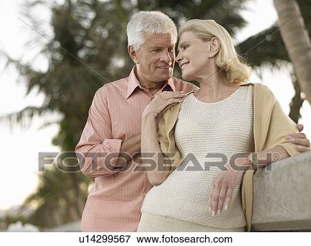 Loving senior couple palm trees in background View Large Photo Image Stock Photo - Loving senior couple palm trees in background. Fotosearch