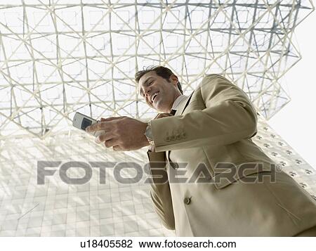 Low angle view of businessman using mobile phone View Large Photo Image Stock Image - Low angle view of businessman using mobile phone. Fotosearch