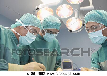 Low angle view of operating theatre with three surgeons at work View Large Photo Image Stock Image - Low angle view of operating theatre with three surgeons at work. Fotosearch