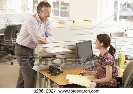 Stock Photo - Male office worker talking to female office worker at cubicle. Fotosearch