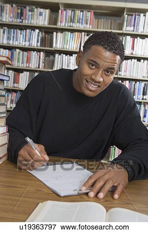 Male student making notes in college library View Large Photo Image Stock Photo - Male student making notes in college library. Fotosearch