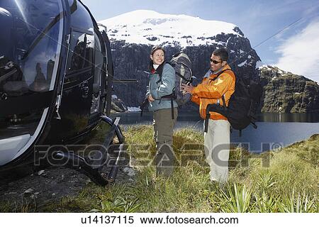 Man adjusting woman's backpack next to helicopter on mountain peak View Large Photo Image Stock Photography - Man adjusting woman's backpack next to helicopter on mountain peak. Fotosearch